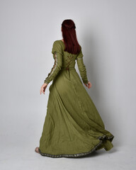 full length portrait of red haired girl wearing celtic, green medieval gown. Standing pose isolated...