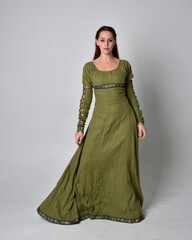full length portrait of red haired girl wearing celtic, green medieval gown. Standing pose isolated...