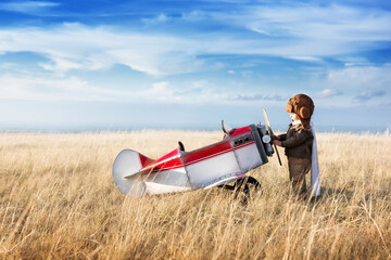 A small child plays with a toy plane, imagines himself as an aviator and dreams of flying. - 423531218