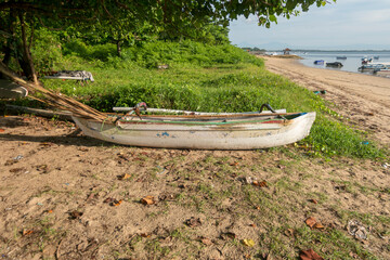 Fototapeta na wymiar Fishing boat by the beach. Fishing boat being repaired in front of the hut by the beach