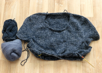 knitted gray-blue sweater, wooden knitting needles and yarn balls, knitting hobby, handmade