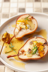 Baked pears with cheese, nuts and honey in a plate on the table.