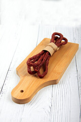 Kabanos or cabanossi - traditional Polish thin dry smoked sausage made of beef and herbs on cutting board close up