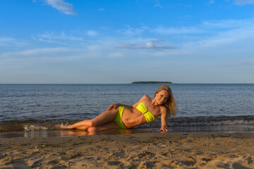 young woman in green bikini posing on a beach