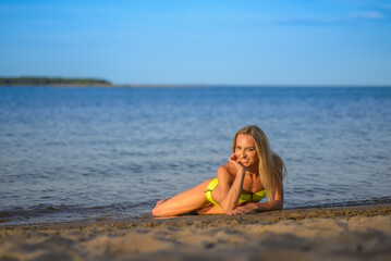 Fototapeta na wymiar young woman in green bikini posing on a beach
