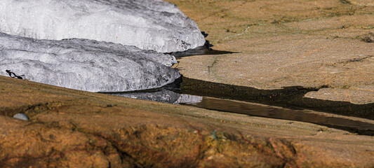 Spring ice melting on rocky shoreline