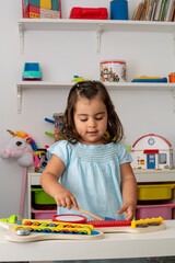 Little girl in kindergarten, playing with a toy musical instrument.