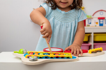 Little girl in kindergarten, playing with a toy musical instrument.