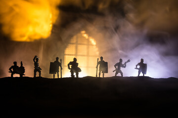 Fototapeta premium Medieval battle scene with cavalry and infantry. Silhouettes of figures as separate objects, fight between warriors on sunset foggy background.