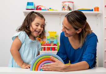 Two-year-old girl and her young kindergarten teacher, playing and learning in kindergarten.