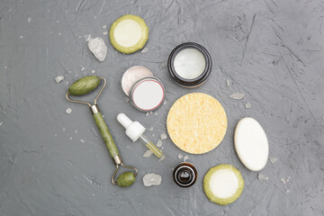 Natural organic skin care product. Home spa and self care products top view. Facial serums, creams, jade roller and various toiletries on textured grey background.