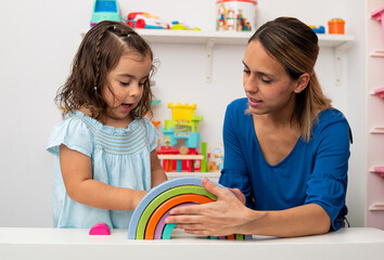 Two-year-old girl and her young kindergarten teacher, playing and learning in kindergarten.