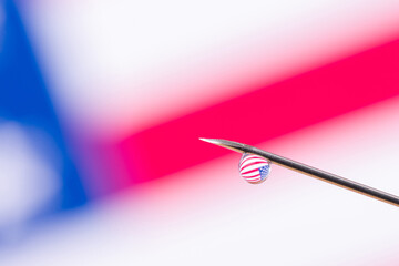Macro photo of a needle of the syringe with a vaccine against the flag of the USA. Concept of vaccination in the United States of America