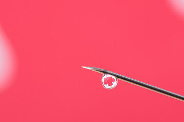 Macro photo of a needle with a drop of vaccine with reflection of a maple leaf against the flag of Canada. Concept of vaccination in Canada