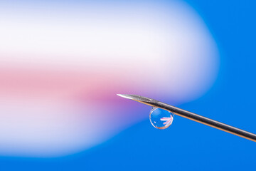 Macro photo of a needle with a drop of vaccine with reflection of the flag of Australia. Concept of vaccination against Covid-19 in Australia