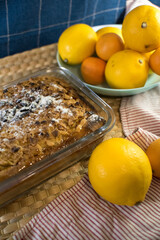 a delicious lemon shortbread pie in a glass baking dish and on a wooden board lies on a towel with ripe yellow and orange citrus fruits on a blue background