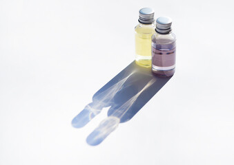 Two perfume bottles and a reflection from them. Fragrant oil in transparent jars. Openwork shadows.
