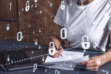 A businesswoman in casual wear signing the contract to prevent probability of risks in cyber security. Padlock Hologram icons over the working desk.