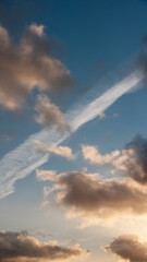 Rastro de avión en cielo azul con nubes blancas