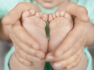 parents hold baby's small feet, concept of caring for family love and happiness