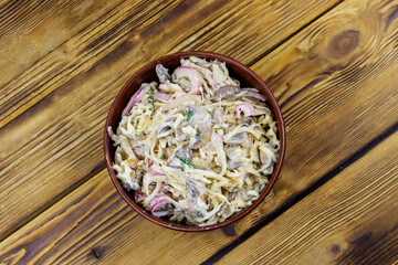 Fototapeta na wymiar Tasty salad of grated celery root, mushrooms, onions on wooden table. Top view