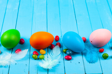 Eggs, candies and feathers on a blue wooden background