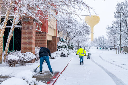 Men move fast to clear snow falling in a business park