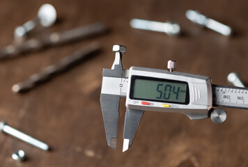 Modern electronic caliper on blurred wooden background. Measurement of inner diameter of nut....