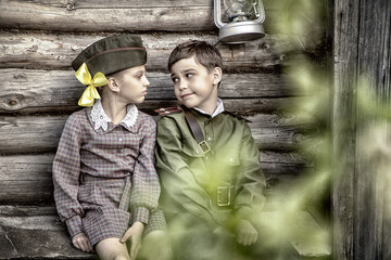 Postcard, stylized as vintage for the Victory Day. A boy in a military uniform and a girl in an old...