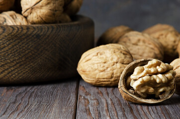 Walnuts on a dark brown wooden background. Close up. Selective focus, side view. Copy space.