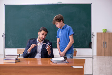 Young male teacher and schoolboy in the classroom