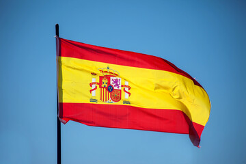 Spanish national flag waving against blue sky