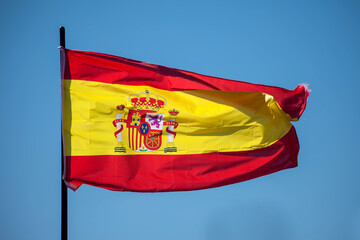 Spanish national flag waving against blue sky