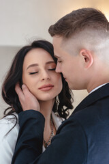 Beautiful heterosexual couple smiling and hugging. Girl in a white trouser suit. Close-up portrait