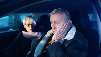 Elderly couple in the car confused with flashing police lights. Speeding ticket. Man and woman having argument in the car. High quality photo