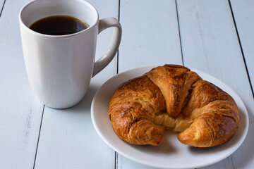 a fresh croissant served with a cup of  coffee