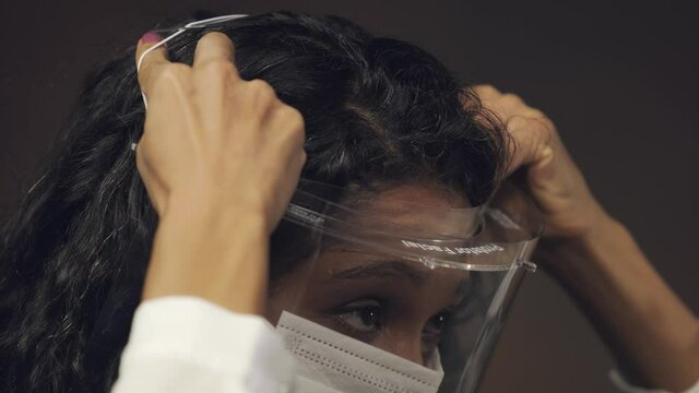 Close up of a doctor or nurse putting on a face shield for virus protection