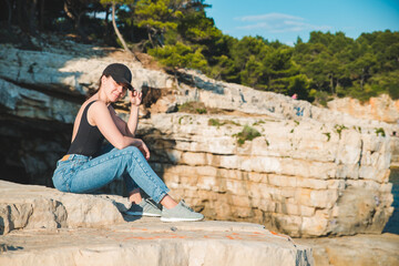 Fototapeta premium young pretty woman sitting on the cliff looking at sea