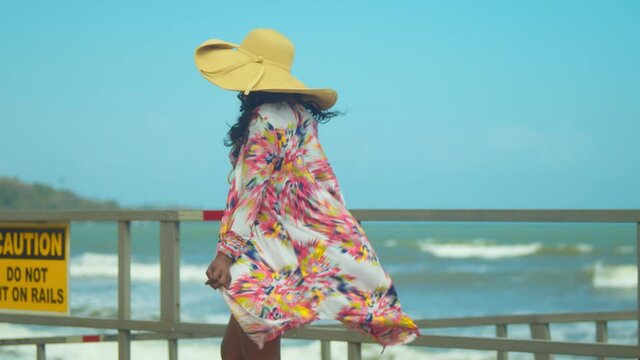 Sexy black woman walks on the beach with her dress blowing in the wind revealing a bikini