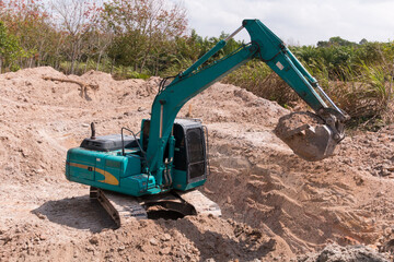 green excavator during earthmoving at construction site. Backhoe dig ground for the construction ...