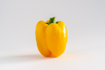 A single whole yellow bell pepper on a white background with copy space