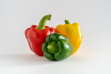 Close-up of a group of bell peppers, green, yellow and red on a white background with copy space