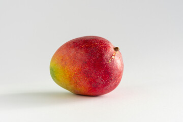 Close-up of a delicious ripe mango with sap near the stem on white background, with copy space, horizontal
