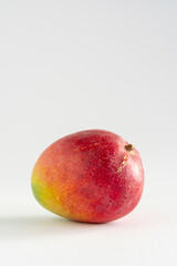 Close-up of a delicious ripe mango with sap near the stem on white background, with copy space, vertical