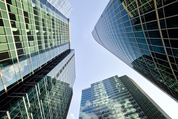 Bottom up view of modern office buildings in the city's business district. Glass facades of skyscrapers with contrasting highlights and reflections. Economy development, finance and business concept. 