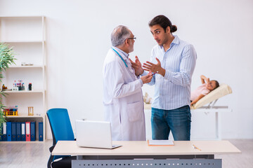 Small girl with her father visiting old male doctor