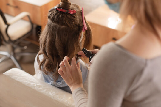 Hairdresser Is Preparing The Girl Hair Style For Photo Shoots. Hairdresser To Curl The Hair In A Beauty Salon, Barber Shop. Reopening The Hair Salons After Pandemic.