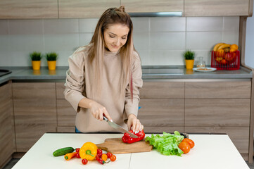 Woman cuts ripe vegetables in the kitchen.