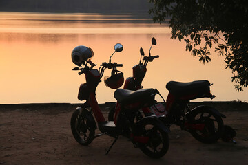 Two electric bikes parked facing the large pond called Srah Srang during sunset