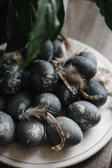 painted blue easter eggs on a plate with bird feathers